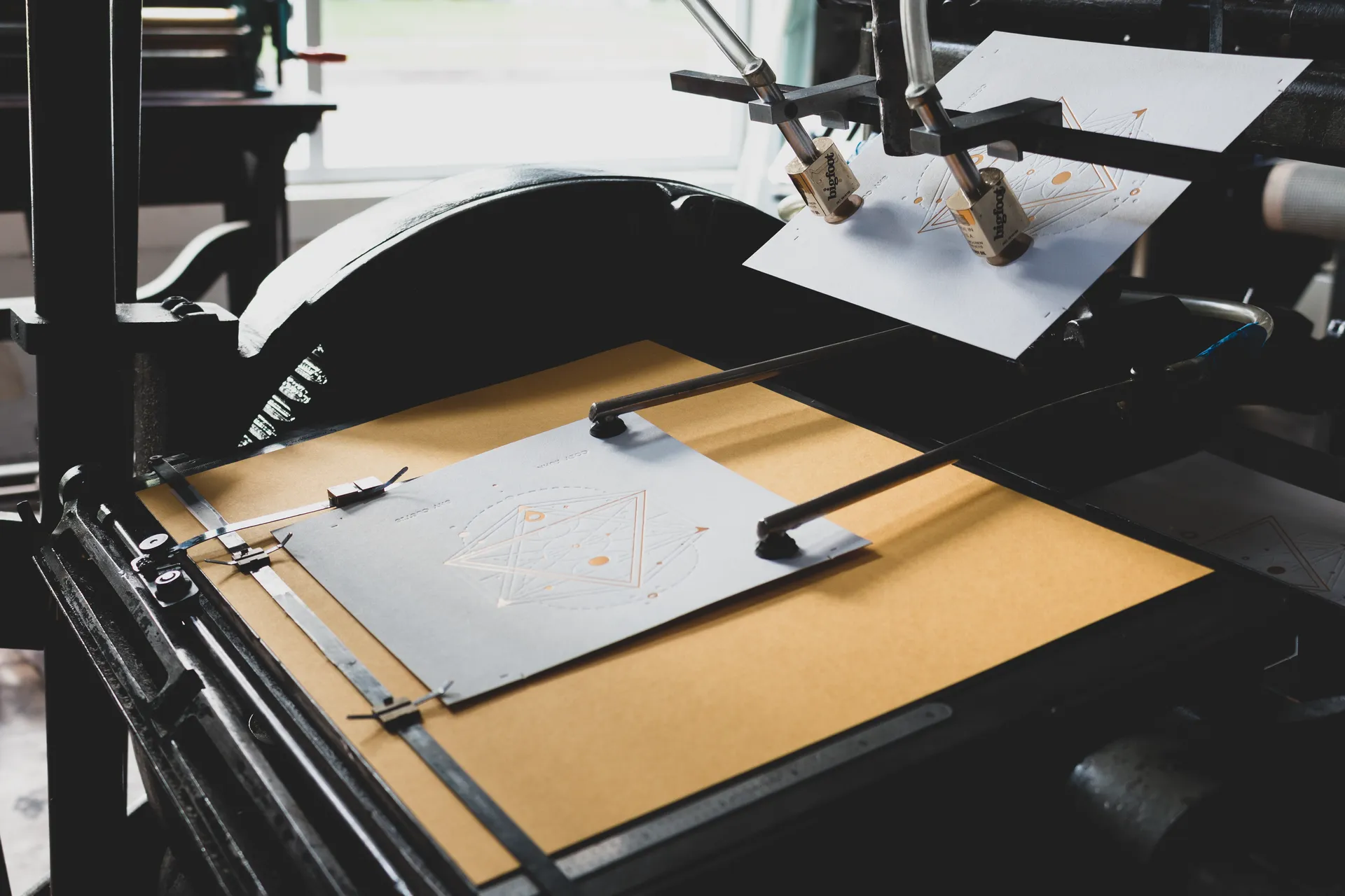 Freshly letterpress-printed art prints with copper foil and blind impression stacked on the press