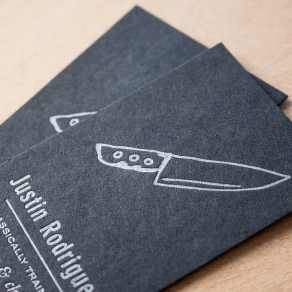 Black paper letterpress business card detail showing silver ink impression
