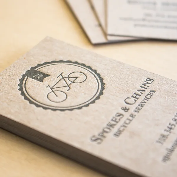 Chipboard letterpress business card with a bicycle illustration in black ink