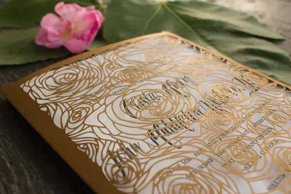 Letterpress wedding invitation with gold laser-cut floral sleeve on white cotton paper