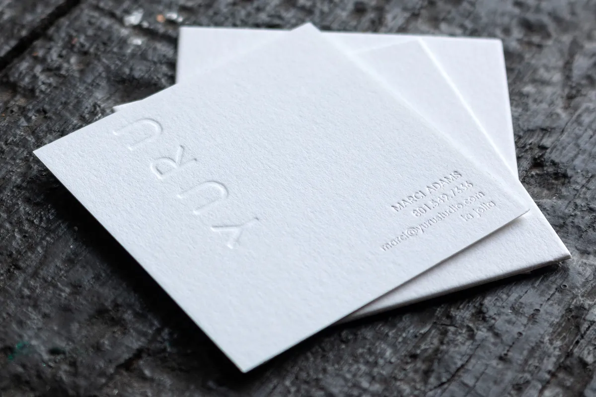 Card backs showing blind debossed YURU wordmark pressed into the cotton paper, with silver foil contact details