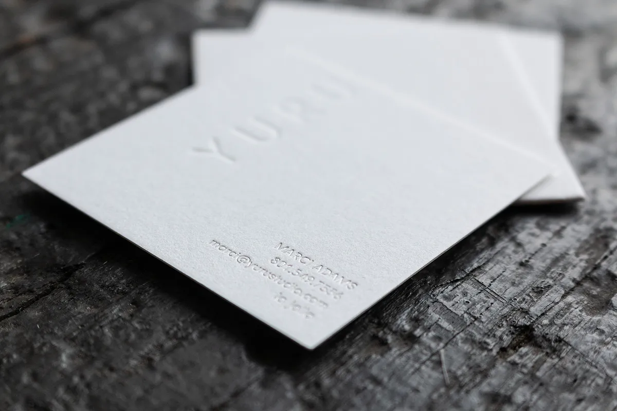 Closeup of the back of a card showing silver foil contact details and the deeply pressed blind debossed wordmark