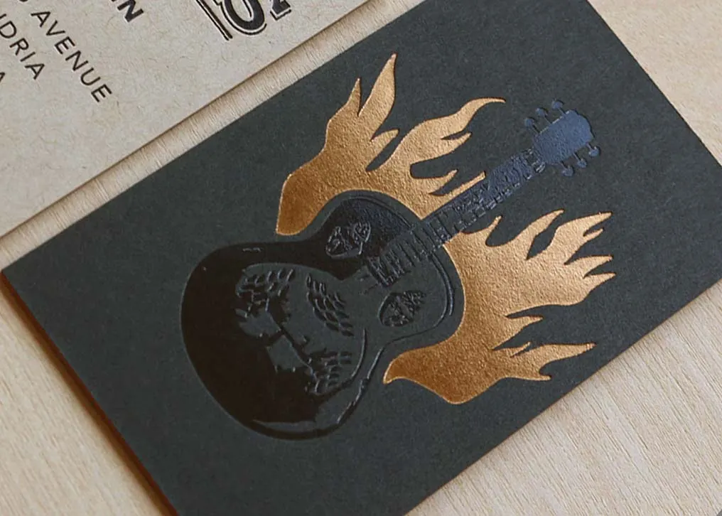 Edge view of a triplexed letterpress business card with a bright orange inner sheet sandwiched between two outer layers