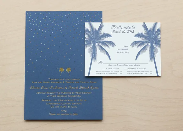 Blue wedding invitation with gold foil starfield pattern beside a palm tree RSVP card