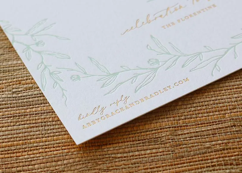 Close-up of gold foil stamping on floral design elements of the wedding invitation